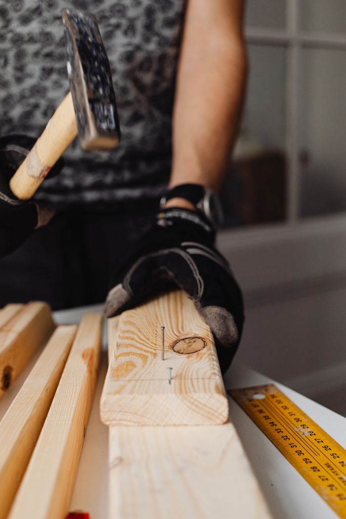 Close-up of a craftsman using a hammer in a woodworking project, highlighting skill and precision.